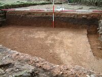 Plate 6. The sectioned floor. A thin crust at first gave the impression of good condition, however below the surface the concrete was powdery and crumbly. A black ashy deposit immediately below the floor, and against wall D of the 2nd C. villa, echoes the gently sloping ground to the left(east) of the wing. The walls are trench built.