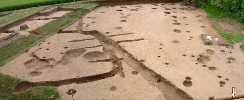 Plate 30. The Iron Age gullies and postholes looking south. The timber building is now almost lost amongst the numerous earlier postholes. The much later 4th century mortar pit is centre right. left in situ for reference.